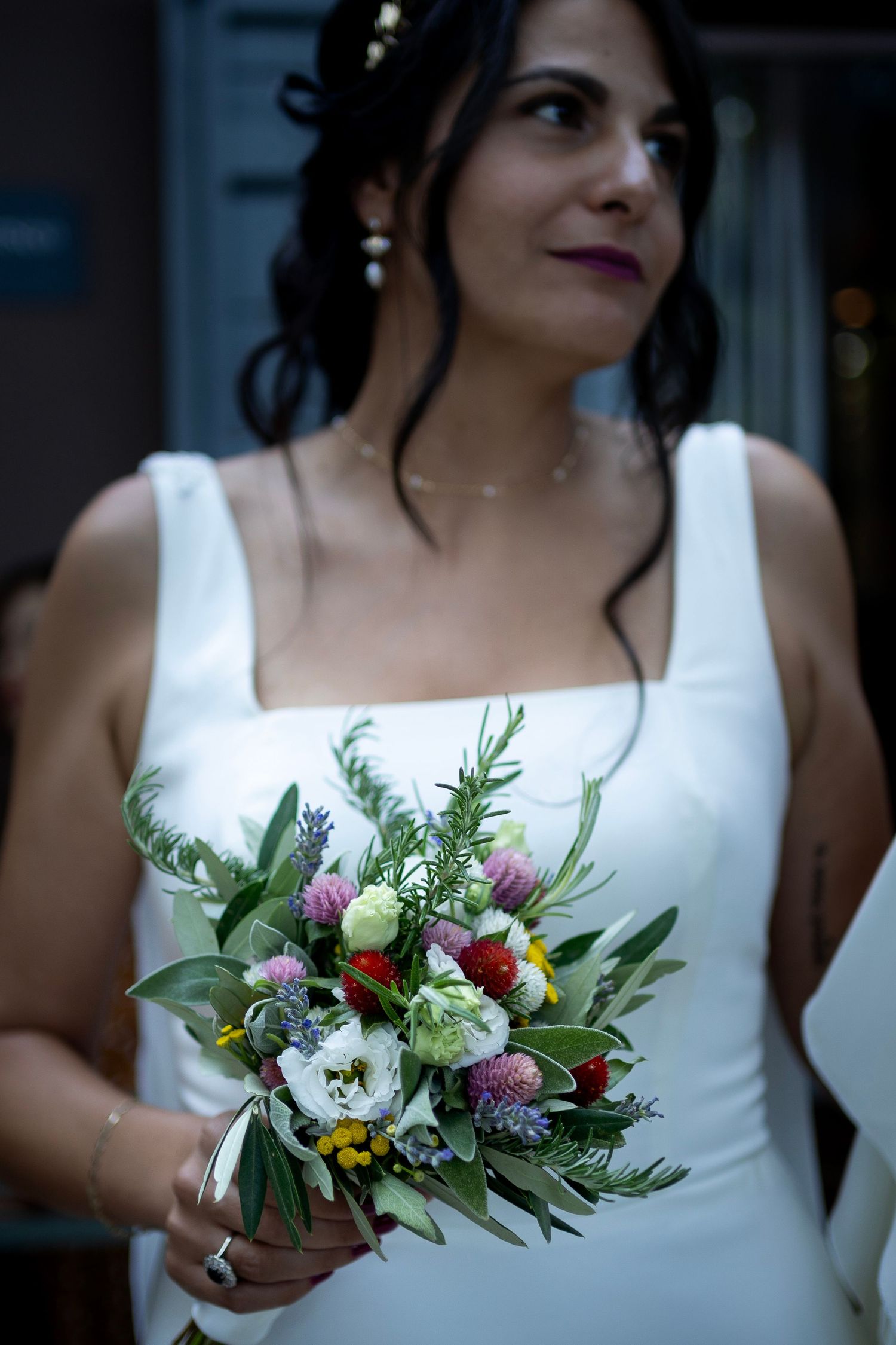 Beautiful bridal bouquet of mixed wildflowers and greenery with white dress.