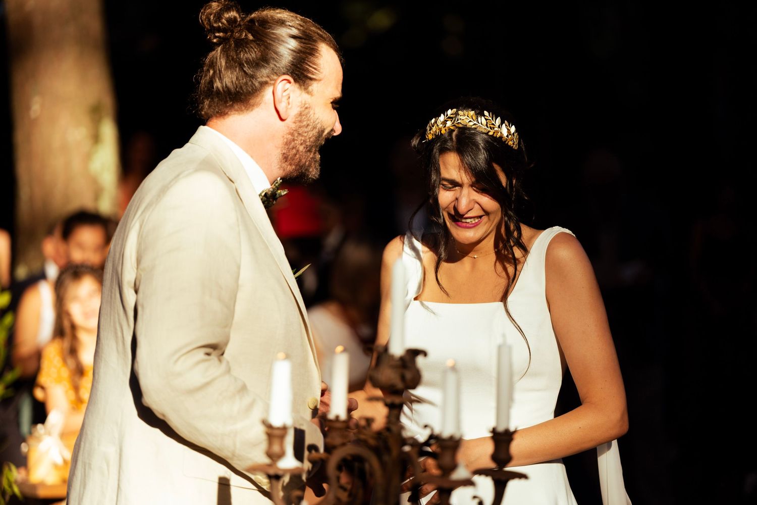 A couple shares a joyful moment during their wedding ceremony with candlelit ambiance.