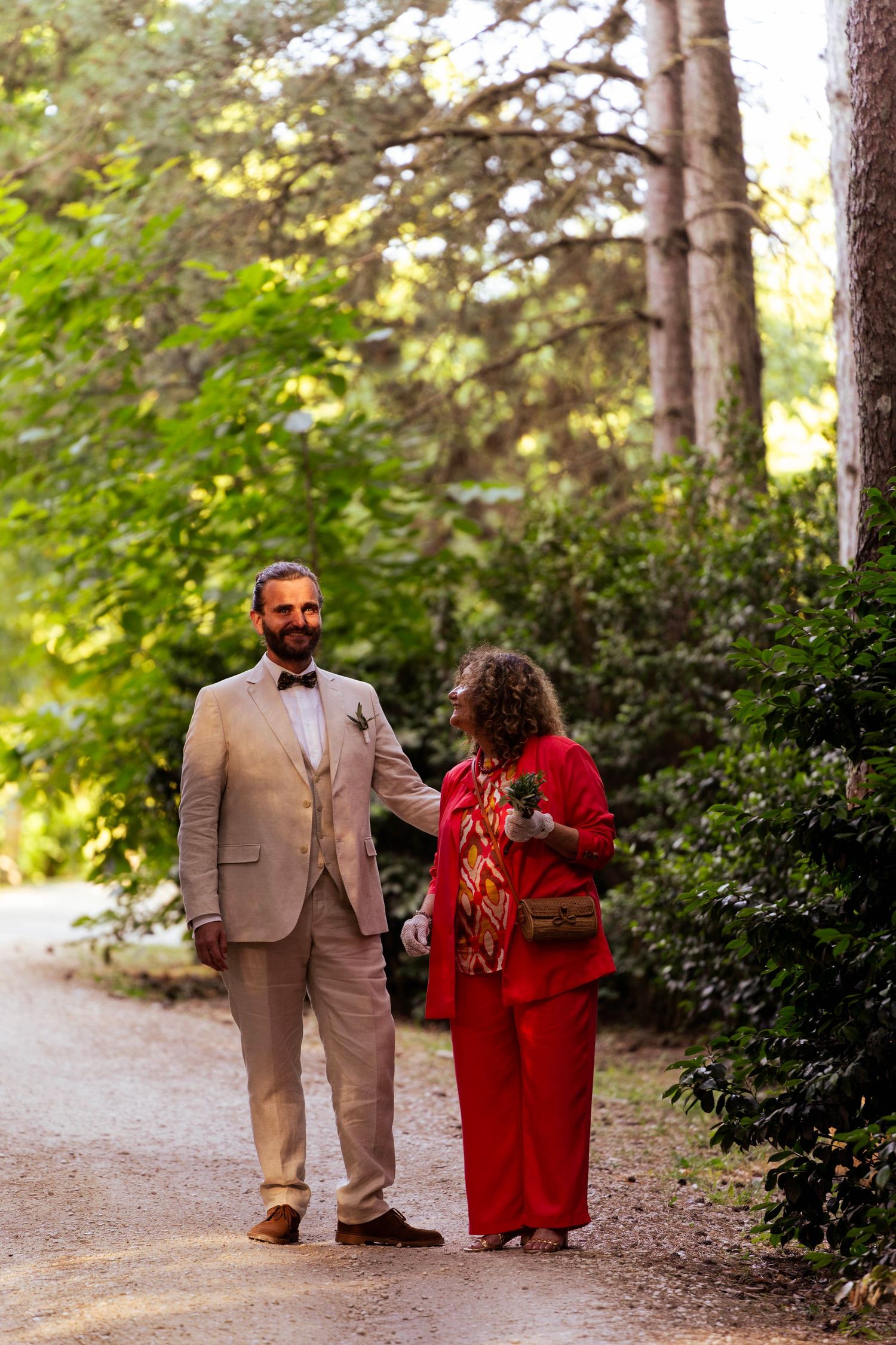 Two people walking along a forest path during a wedding celebration.