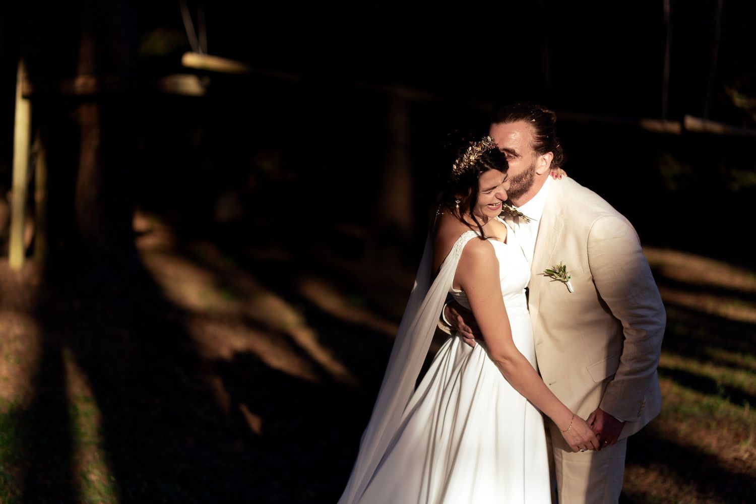 A tender wedding moment captured in a sun-dappled forest clearing.