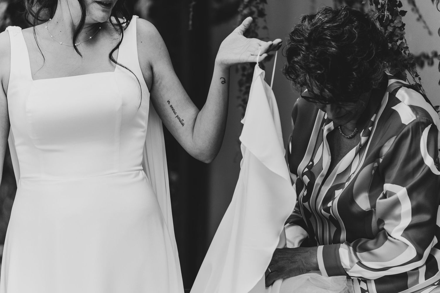 Black and white image of wedding dress preparation with detailed fabric work.