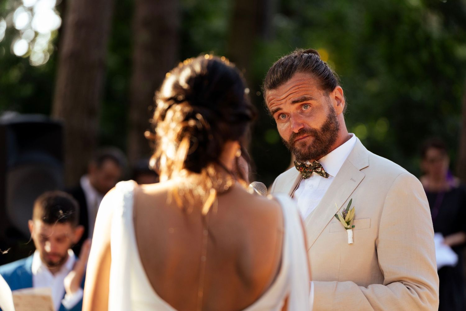 Intimate forest wedding ceremony with soft natural lighting filtering through trees.