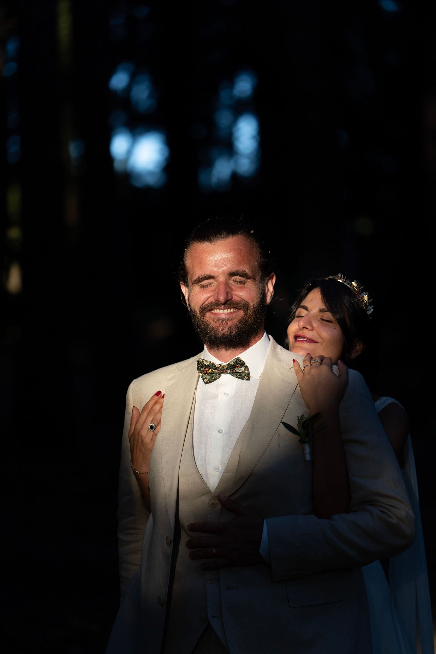A romantic wedding portrait with dramatic lighting in a forest setting.