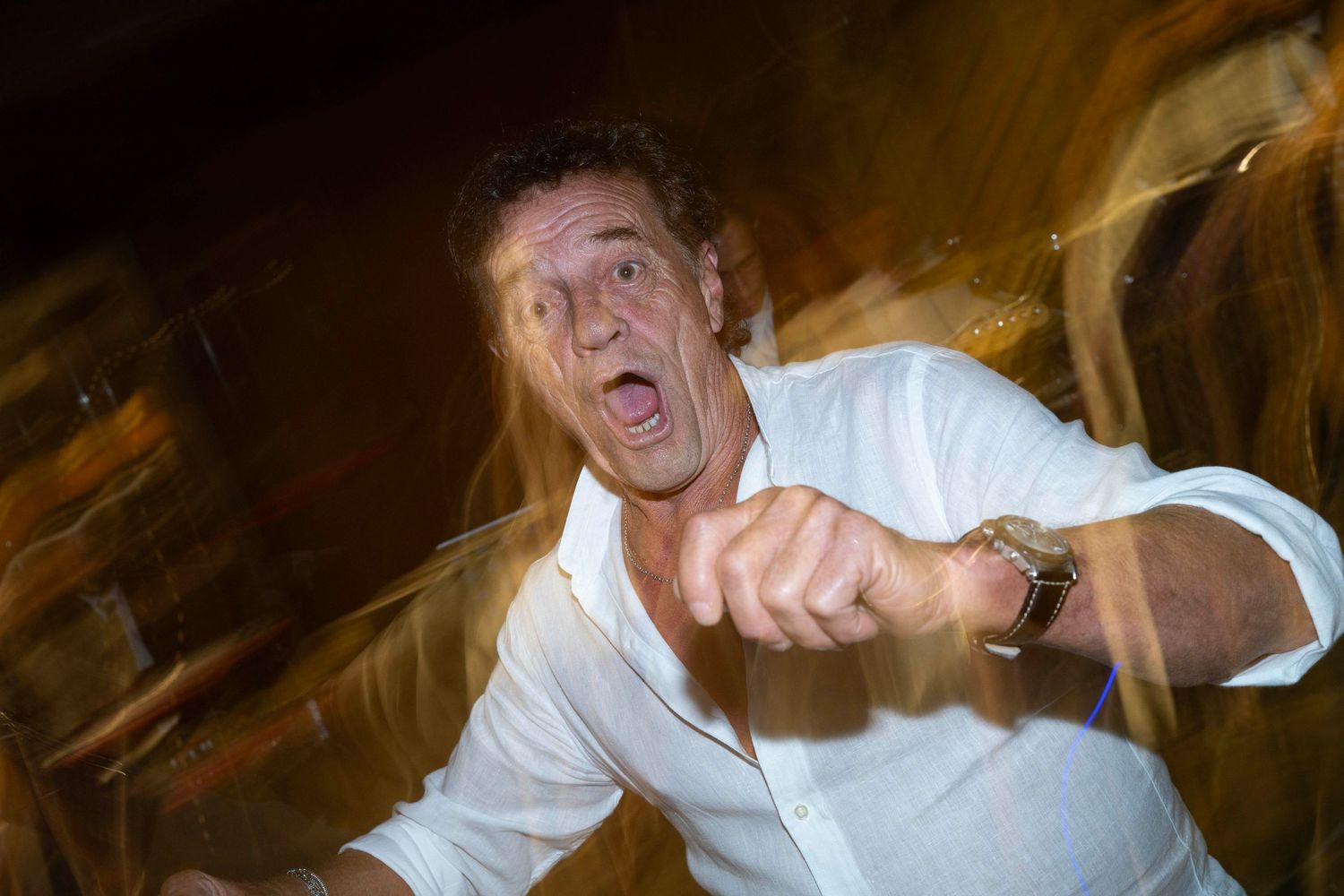 Energetic dancer moves enthusiastically under ambient lighting at a nighttime celebration.