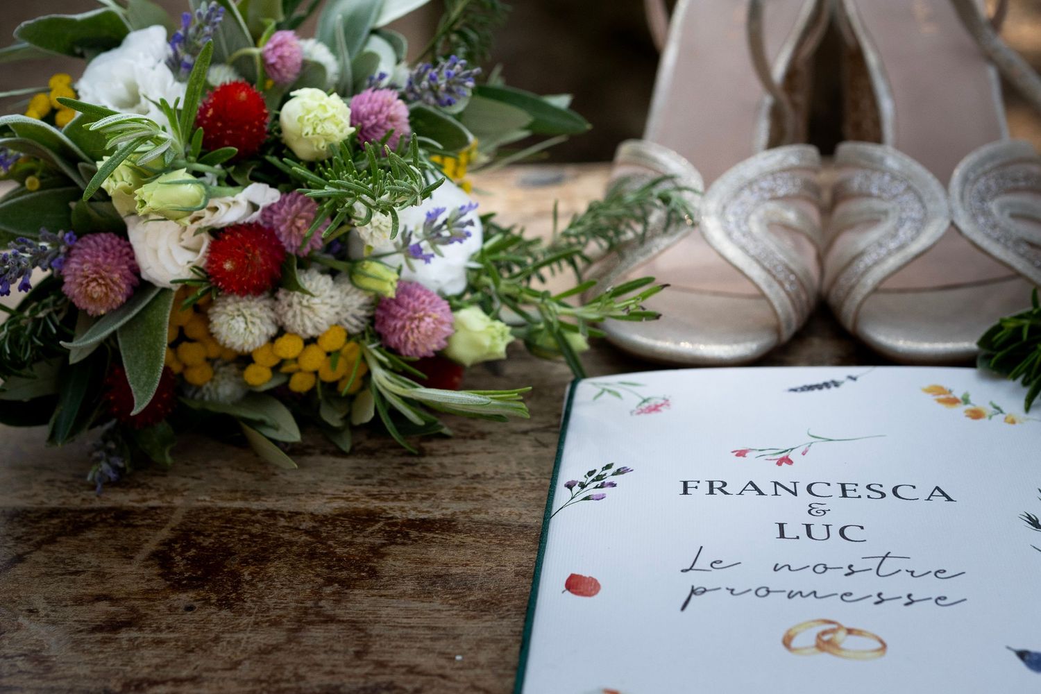 Wedding invitation with colorful floral bouquet and elegant shoes on wooden surface.