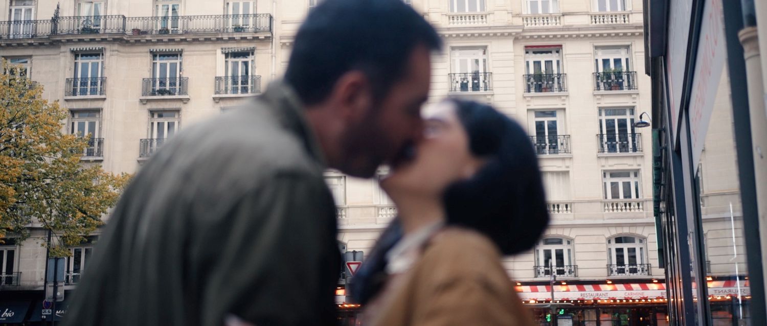 A tender moment shared between a couple outside a historic building in Paris.