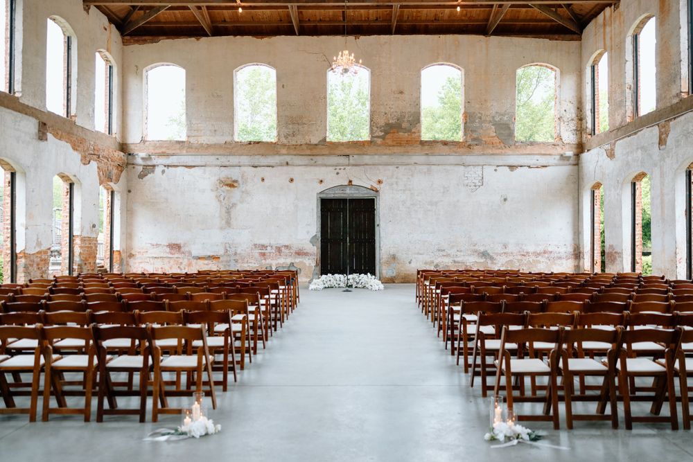 Rustic wedding ceremony venue with wooden chairs and distressed white walls.