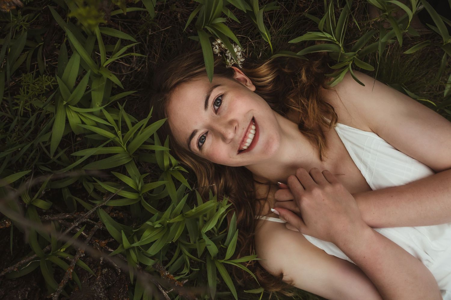 A portrait of someone lying in green grass and flowers with a joyful expression.