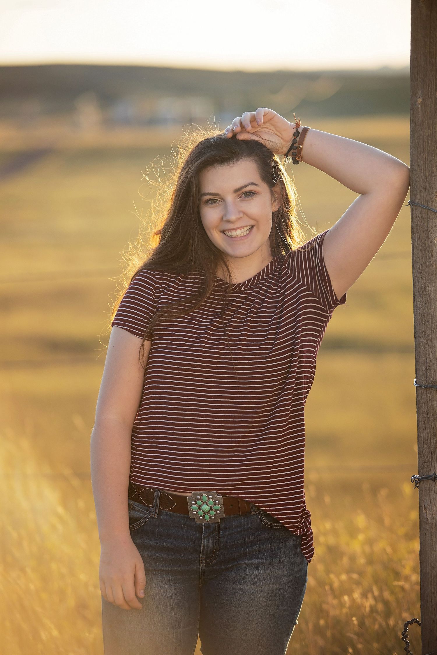Casual outdoor portrait in striped shirt against golden sunset field.