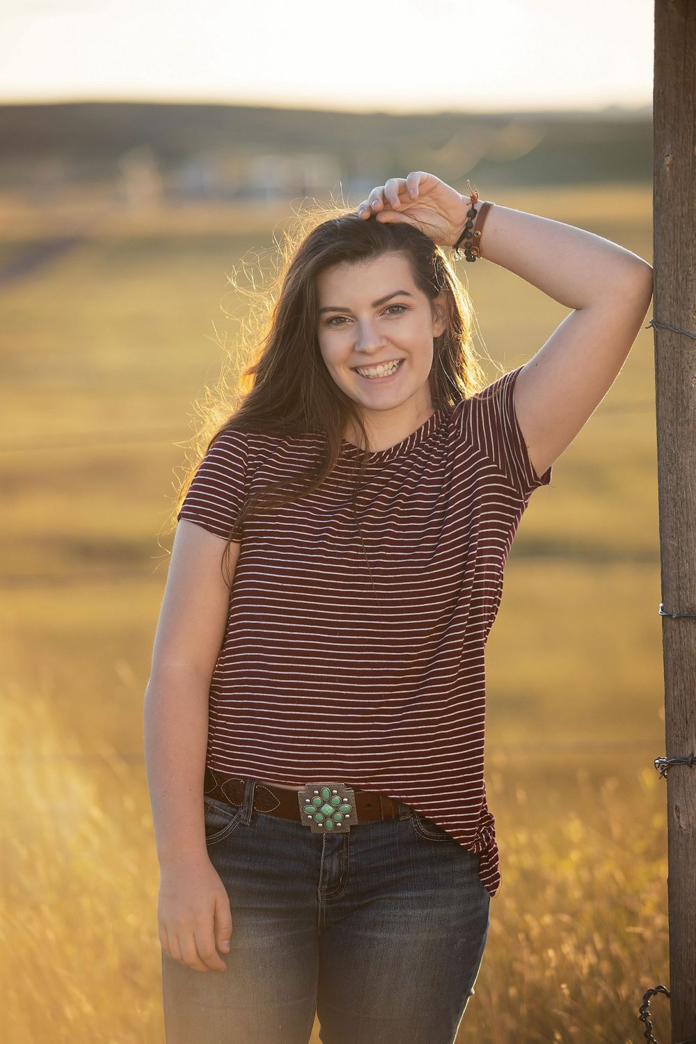 Casual outdoor portrait in striped shirt against golden sunset field.