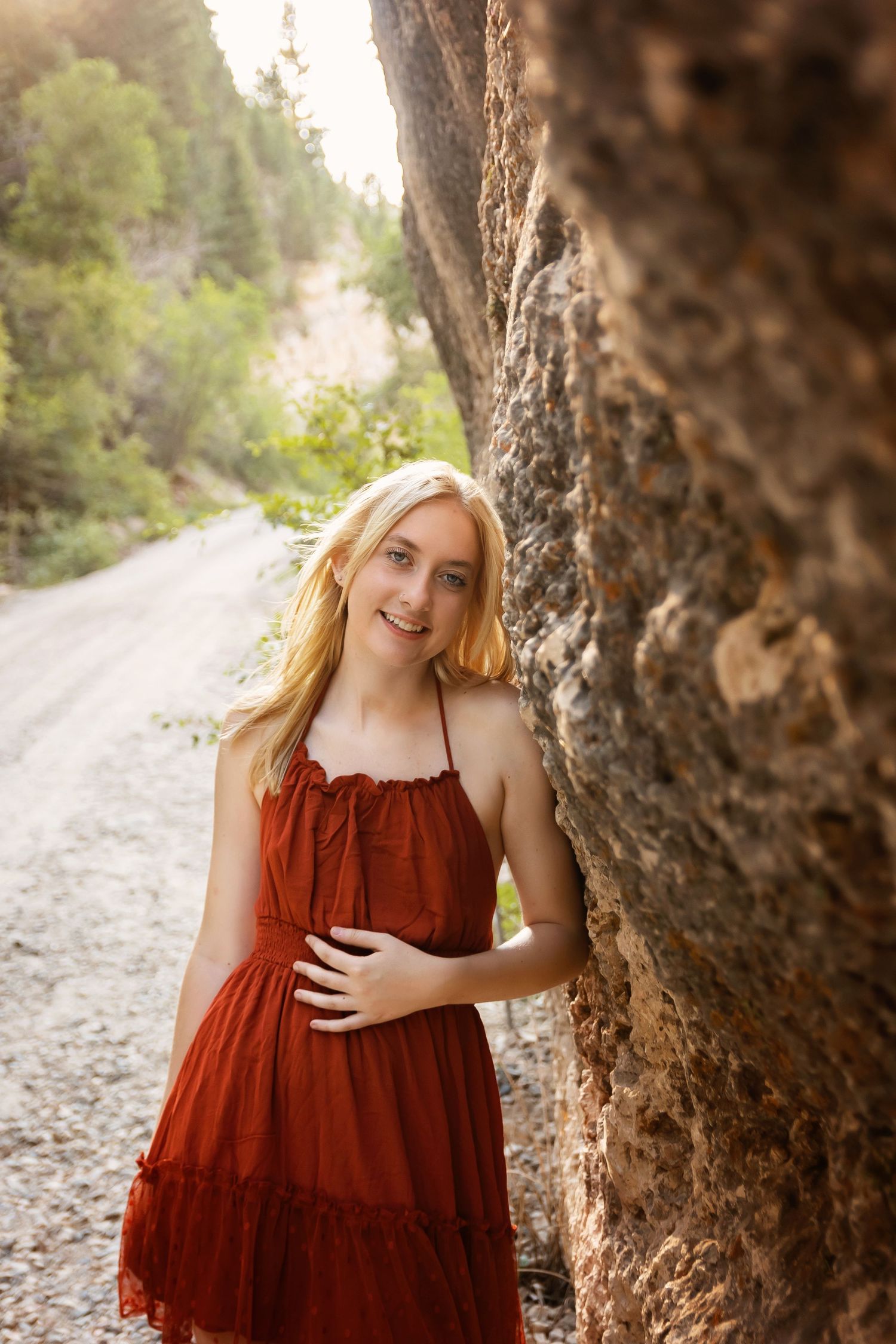 A red sundress stands out against rocky canyon walls on a winding mountain road.