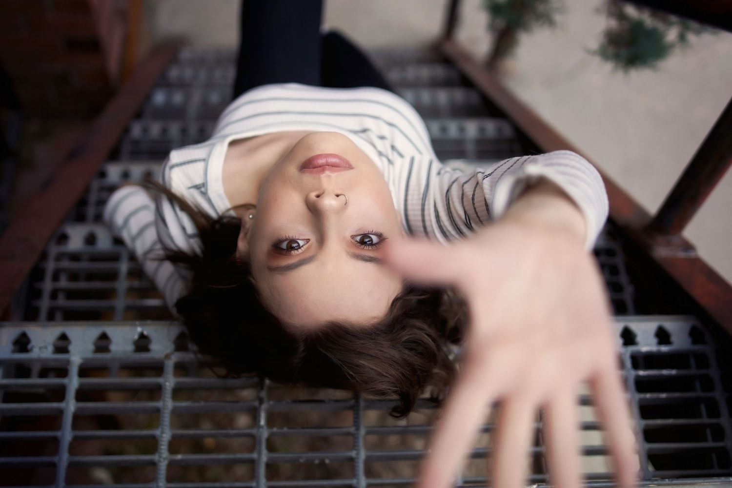 Creative overhead portrait shot lying on wooden slat surface with outstretched hand.