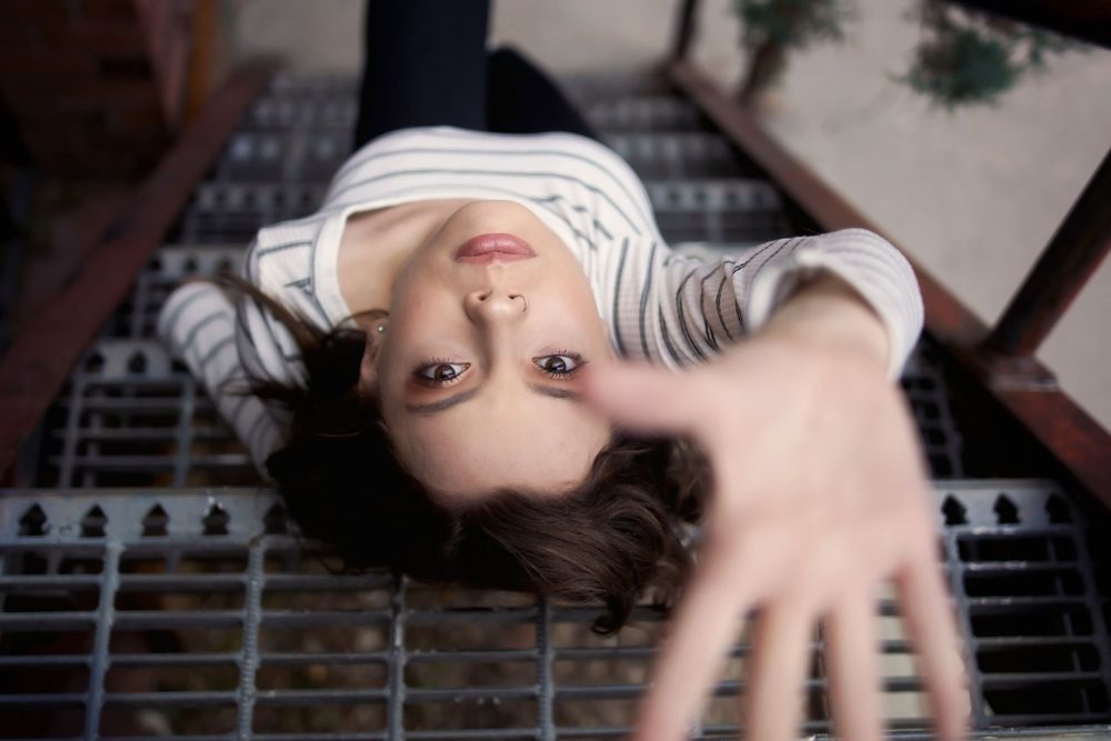 Creative overhead portrait shot lying on wooden slat surface with outstretched hand.