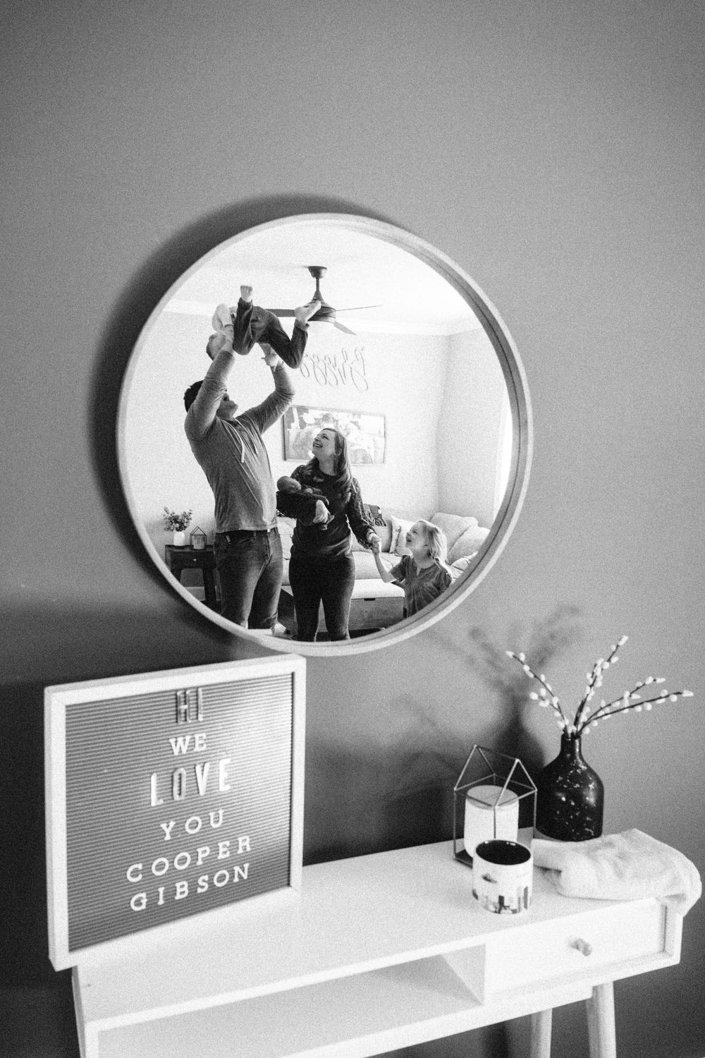 Modern shelf display with oval mirror and decorative text signs in black and white.