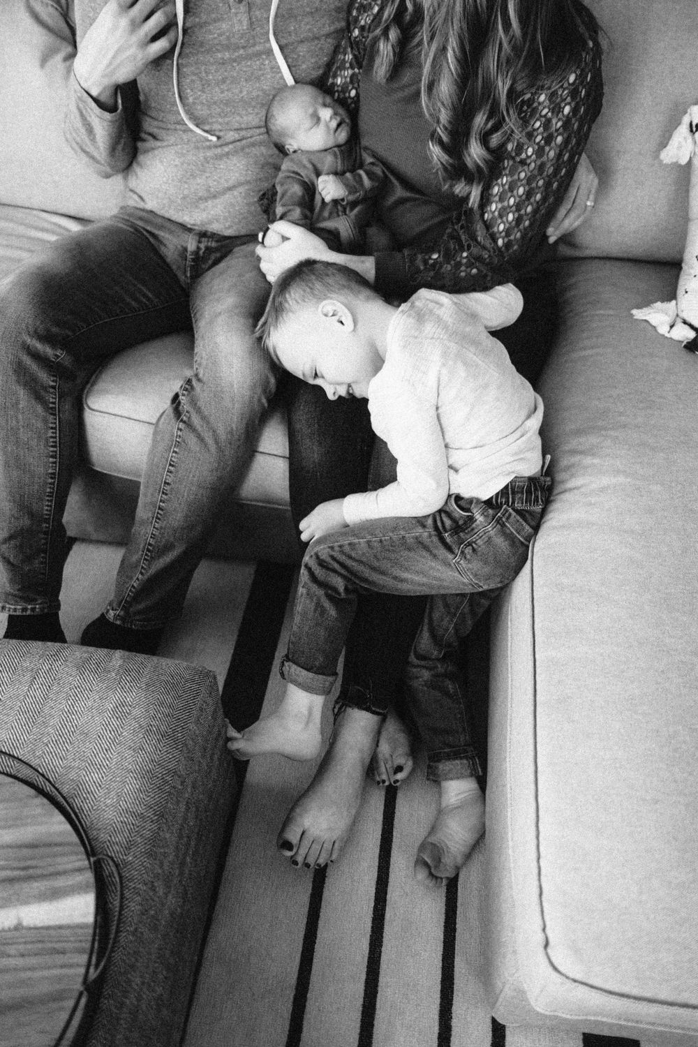 Black and white image showing legs and feet resting on a couch.