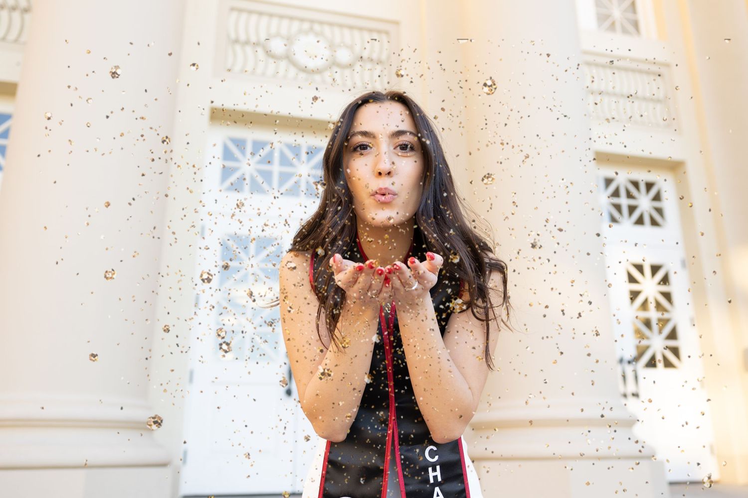 College graduate blowing glitter in the air at Chapman University