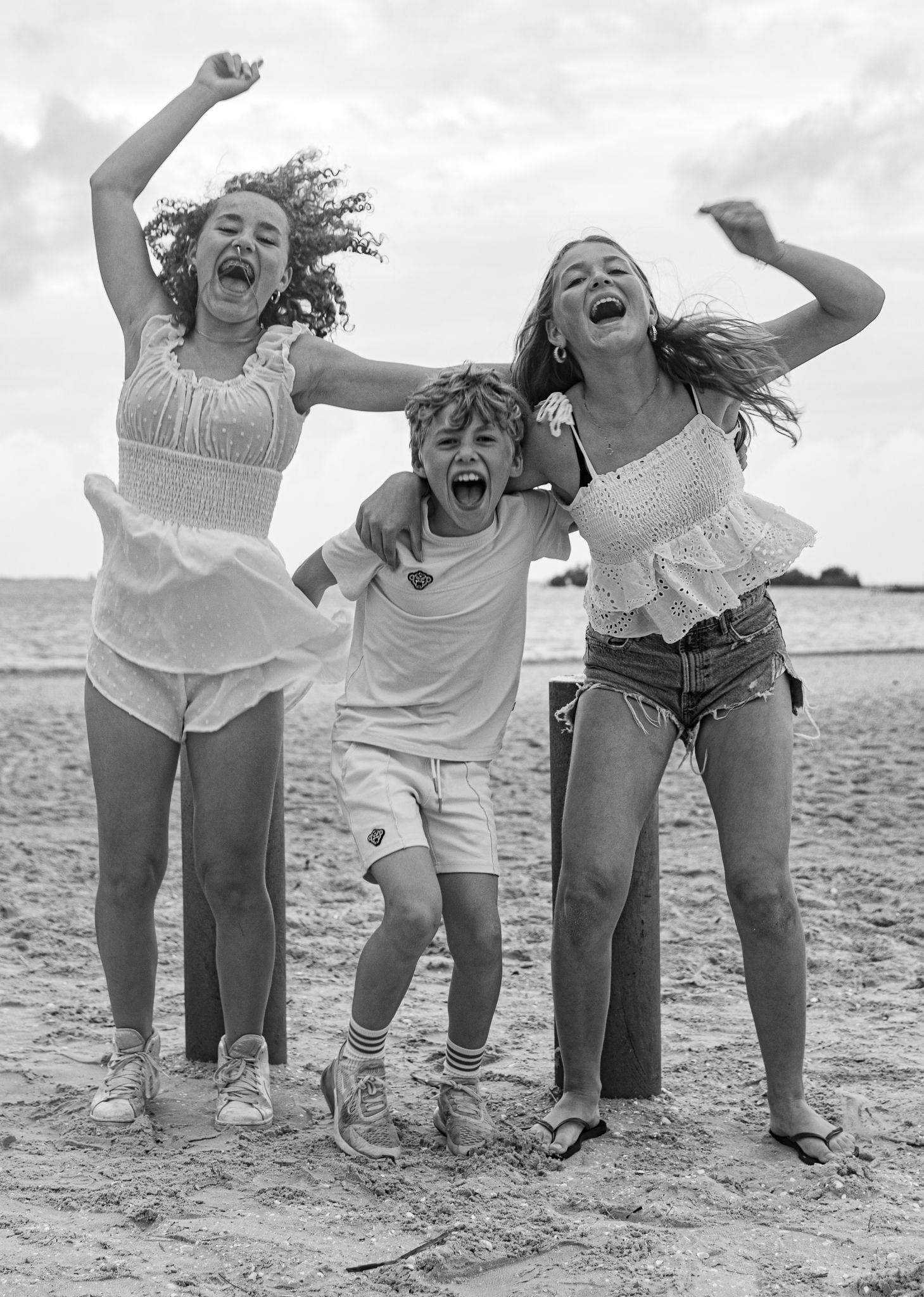 Black and white photo showing joyful movement and laughter while jumping at the beach.
