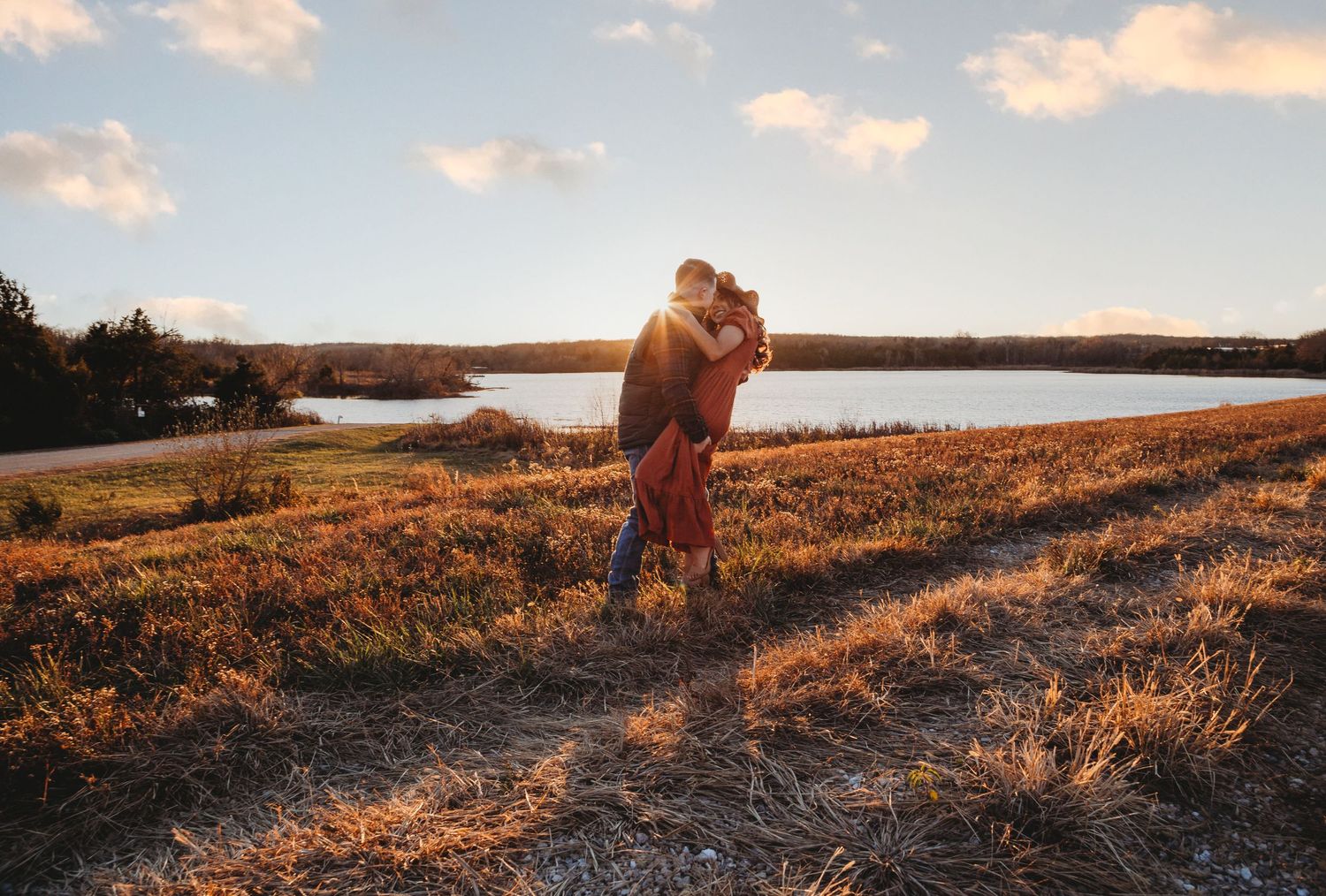 A couple embraces at sunset near a lake