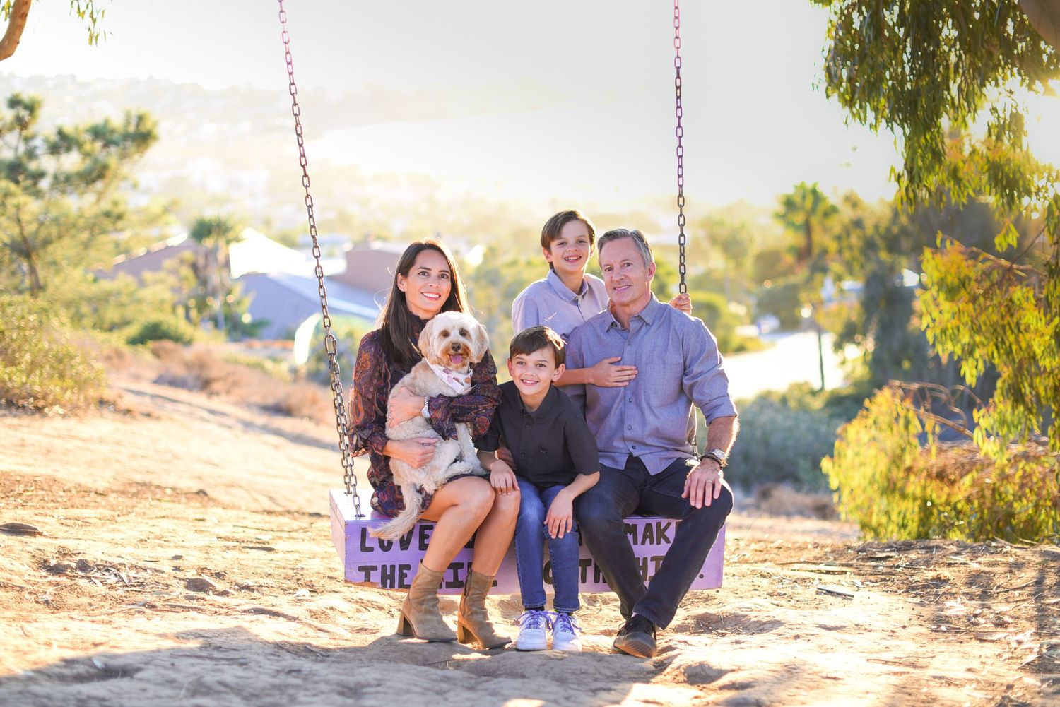Family members sitting and posing together on wooden swings in a park setting.