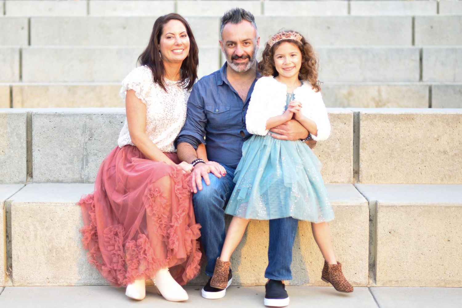 Family seated together on concrete steps for a casual outdoor portrait.