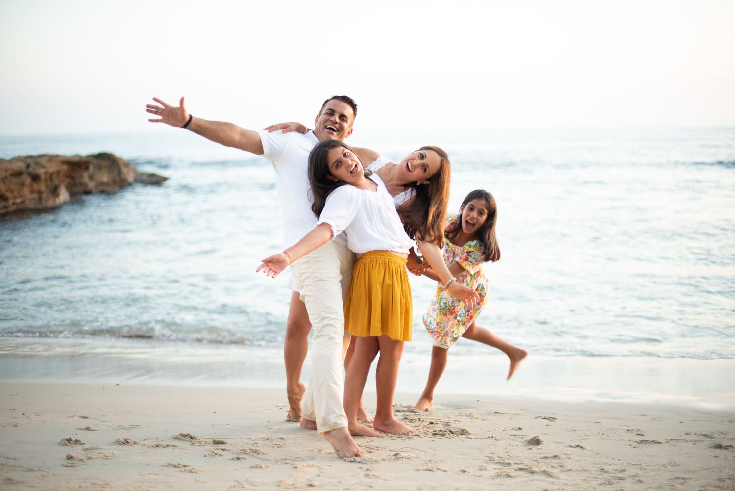 Friends having fun and posing playfully together on a beach at sunset.
