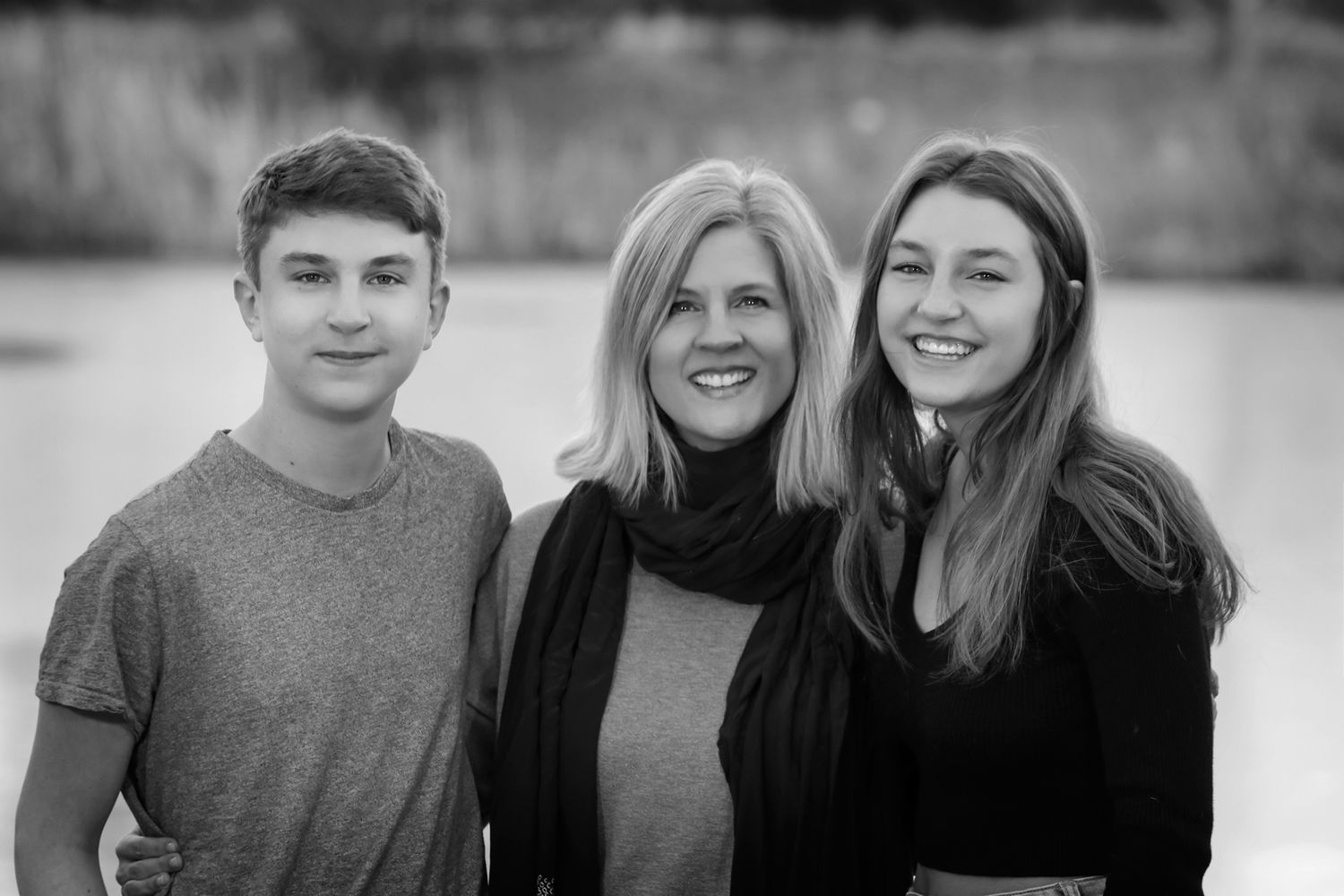 Black and white portrait of three people against light background.
