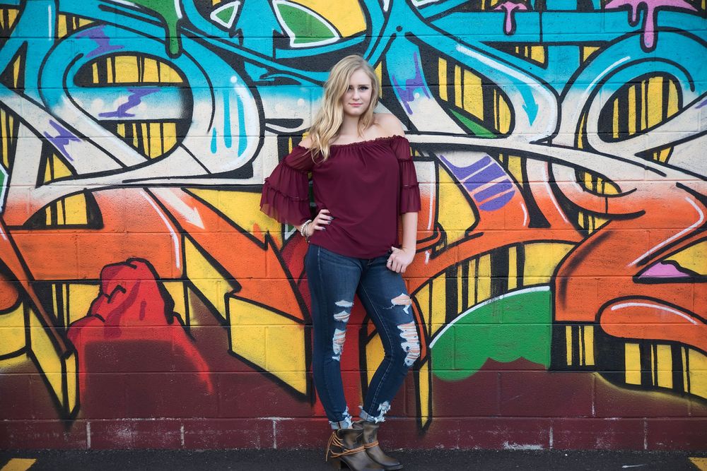 Casual street style portrait against colorful graffiti wall with orange and blue designs.