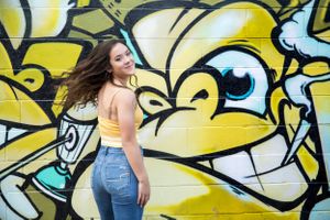 Fashion portrait against vibrant yellow street art graffiti in an urban setting.
