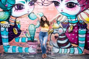 Urban fashion portrait against colorful cartoon character street art mural.