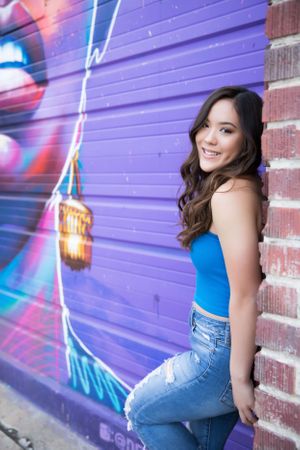 Urban portrait against purple graffiti wall with neon-style artwork.