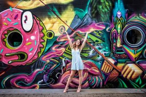 White dress contrasts with colorful street art featuring cartoon donut and neon designs.