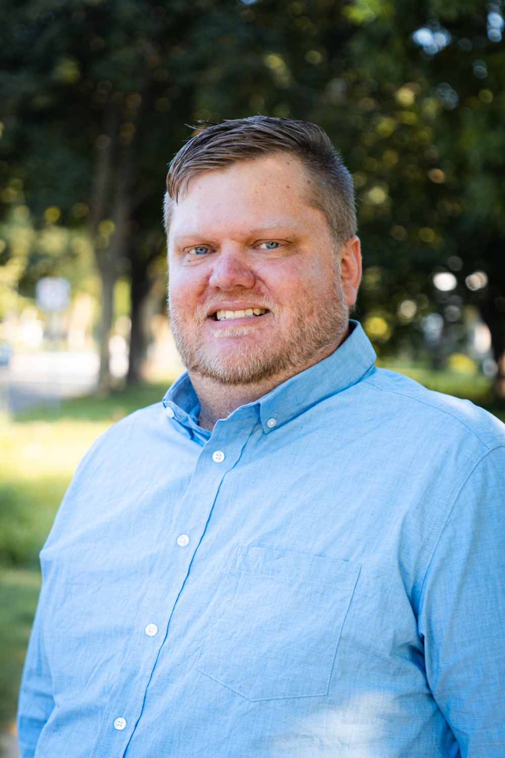 Portrait series of a person in a light blue button-down shirt outdoors with natural lighting.