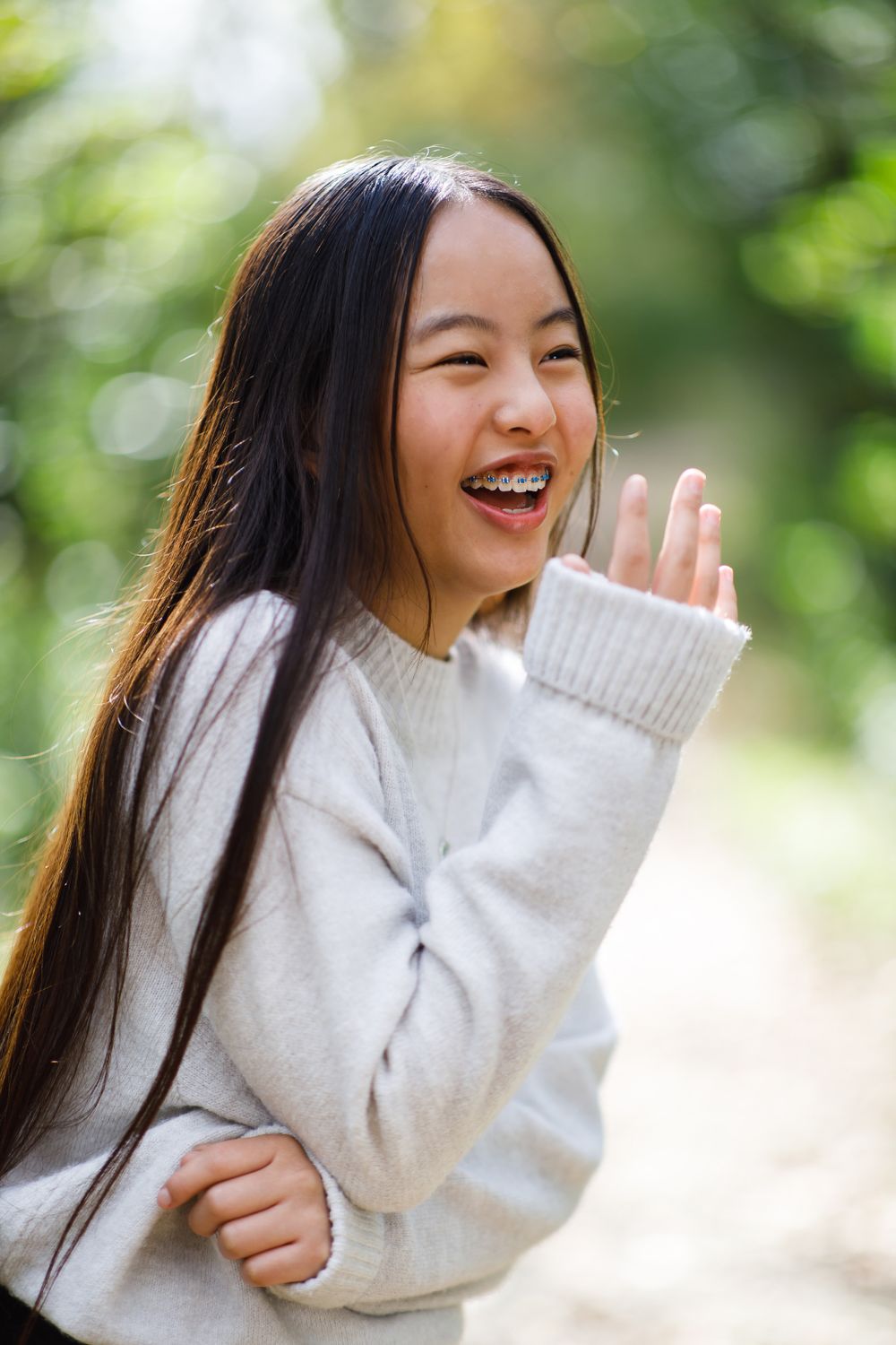 Joyful winter portrait in cream sweater with natural outdoor bokeh.