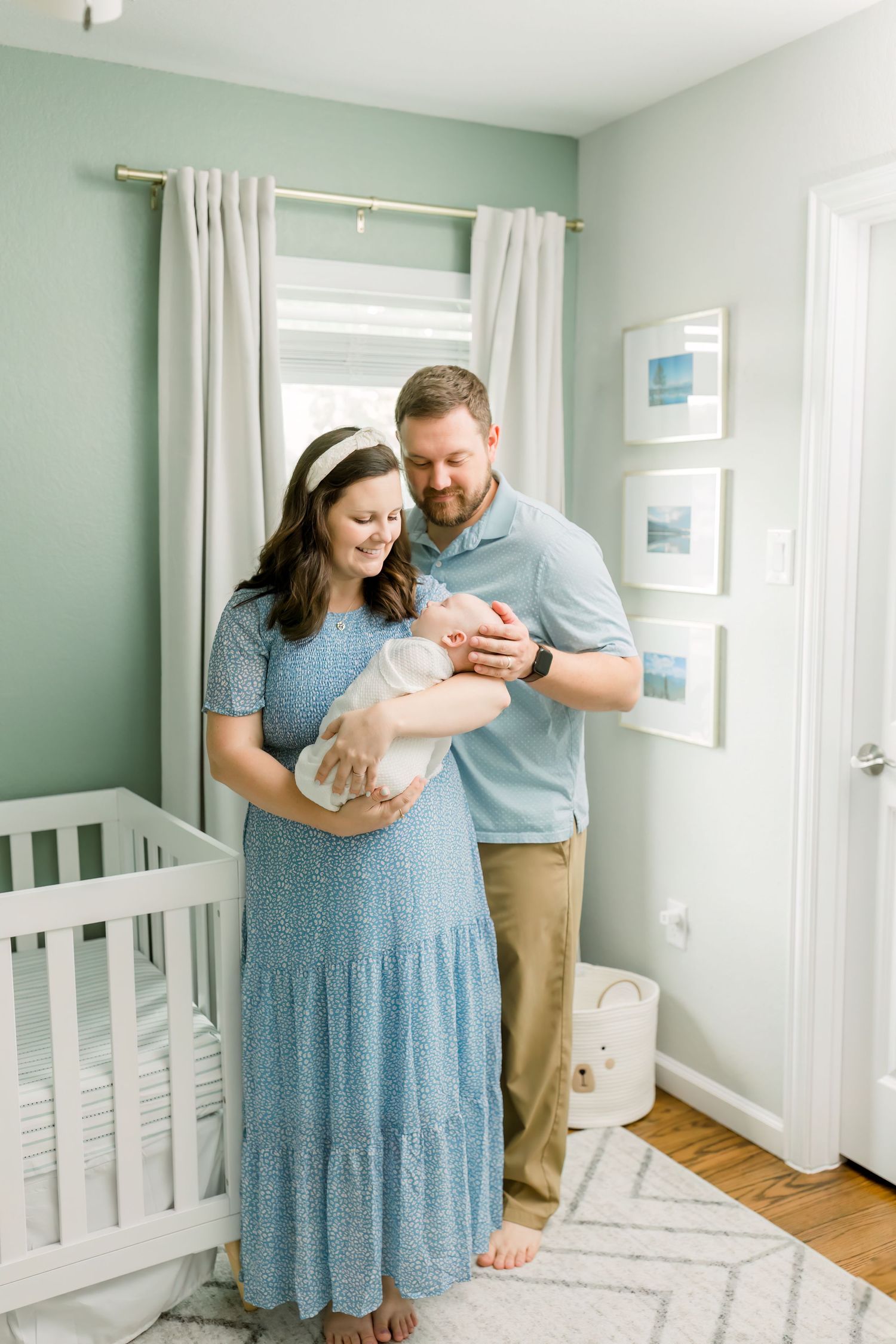 A loving moment captured in a mint green nursery with white crib and framed wall art.