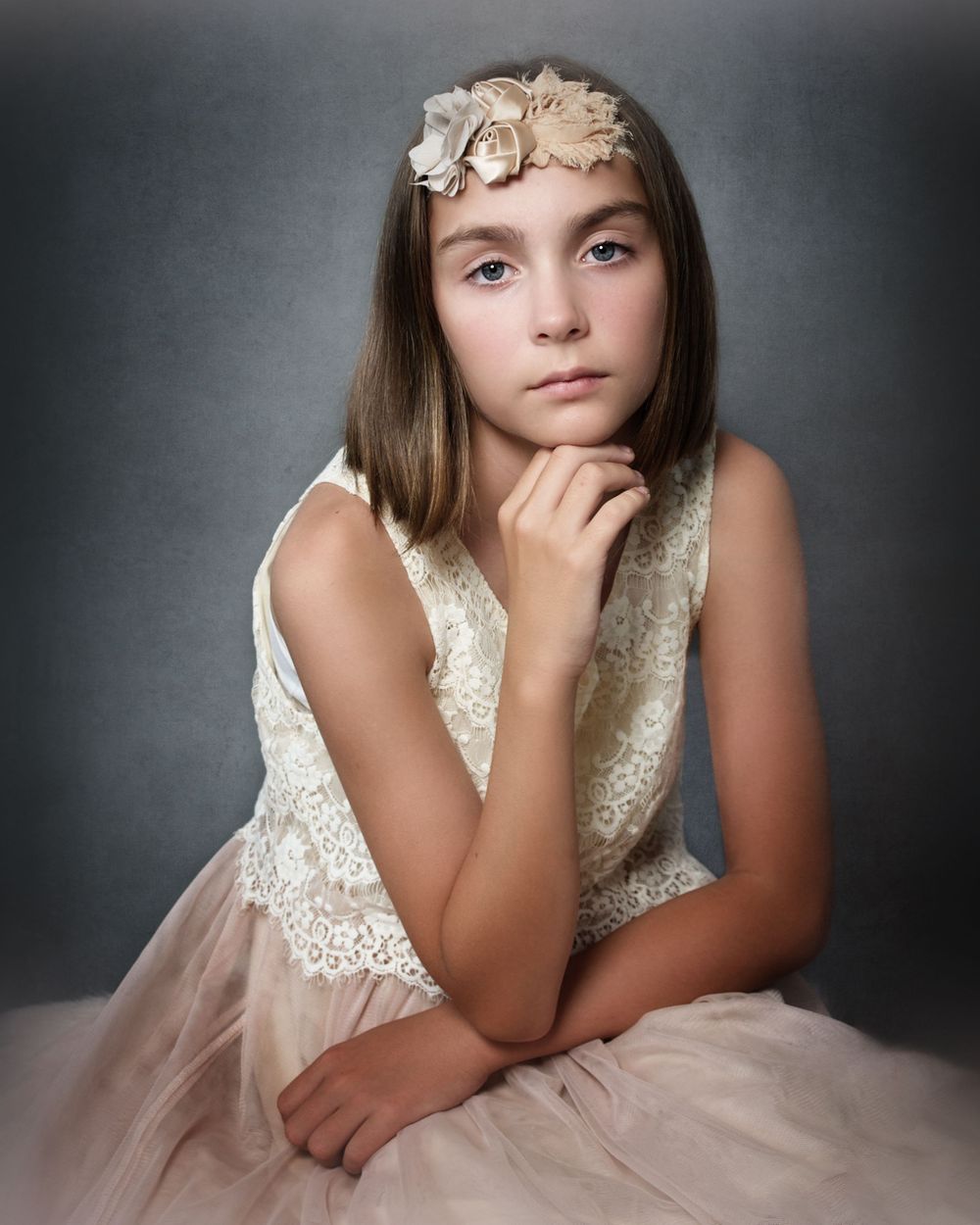 portrait of a tween female in a peach and white dress holding her hand under her chin