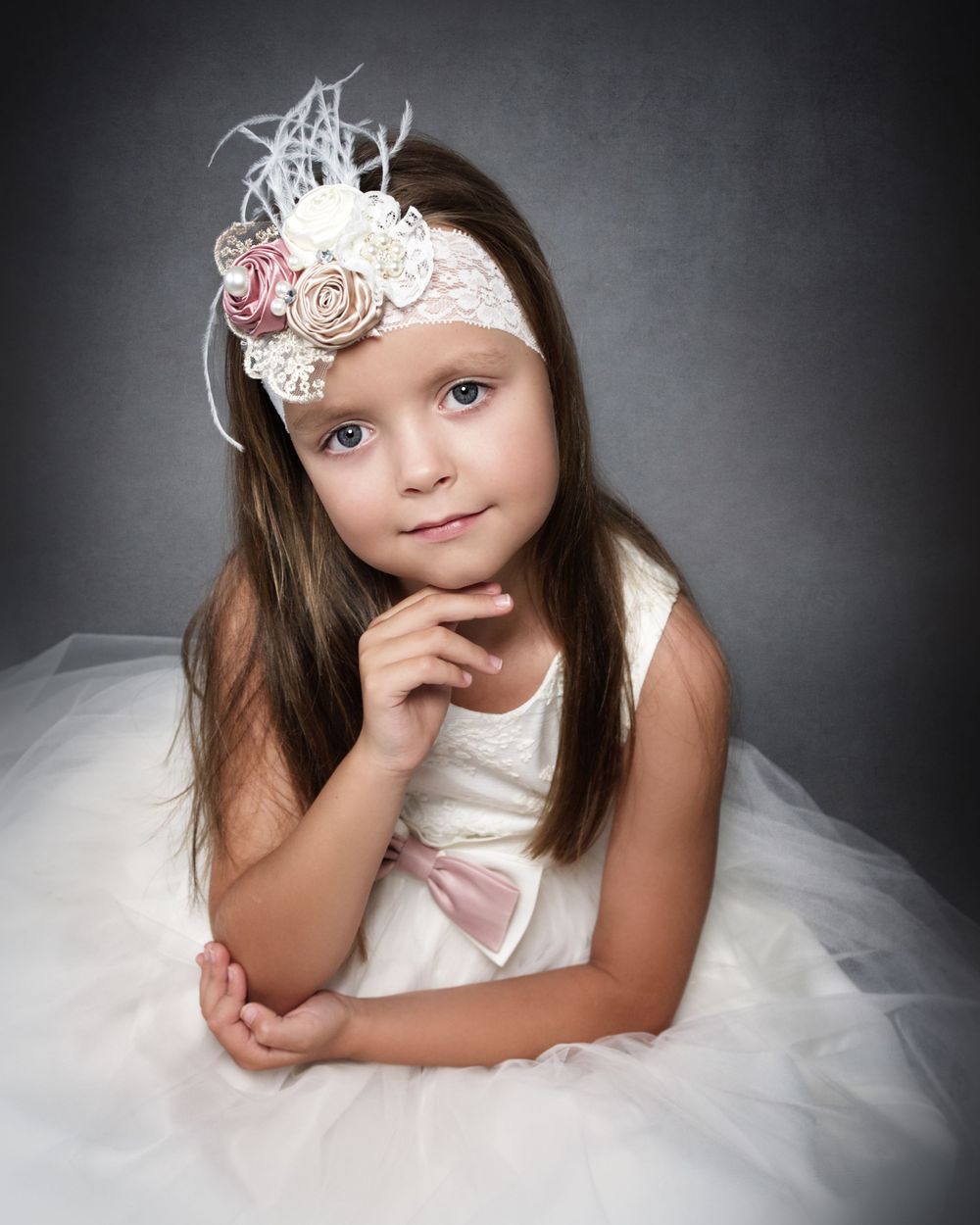 child portrait of a girl wearing a white princess dress and head band with angelic smile