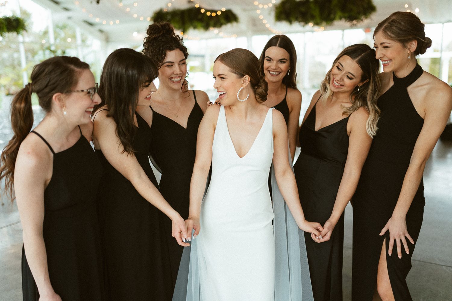 A bridal party in coordinated black and white dresses sharing a candid moment together.