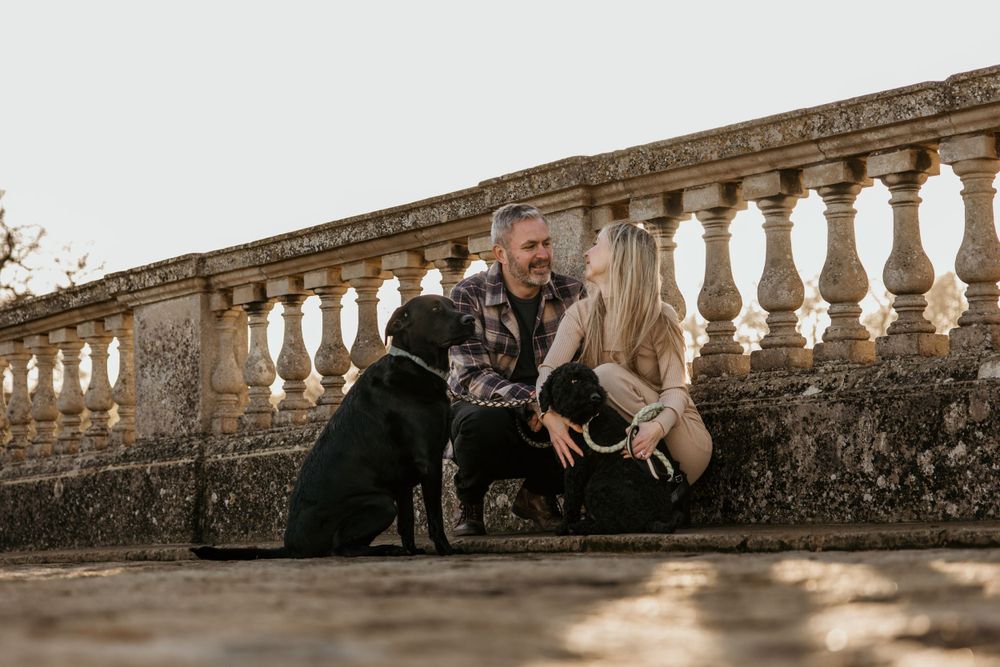 A couple and their black dog sharing a moment on historic stone steps outdoors.