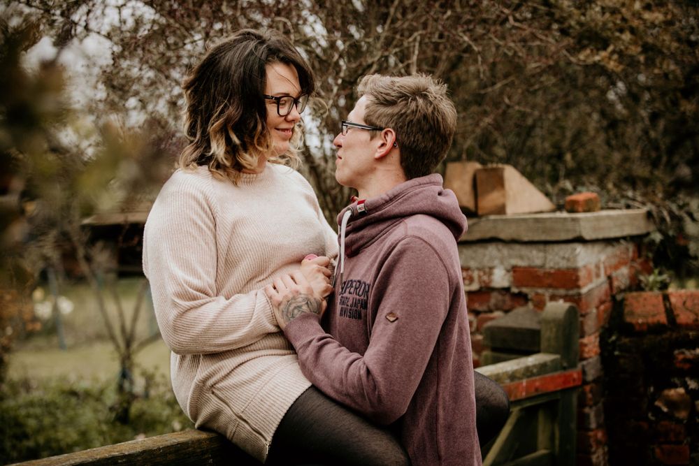 Couple shares an intimate moment in a garden wearing cozy sweaters.