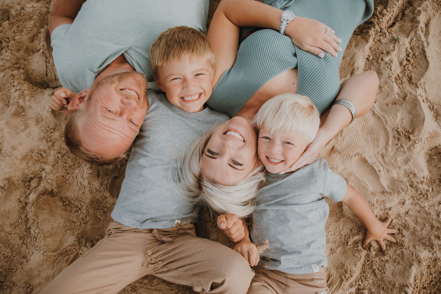 Children lying in circle formation wearing matching gray shirts.