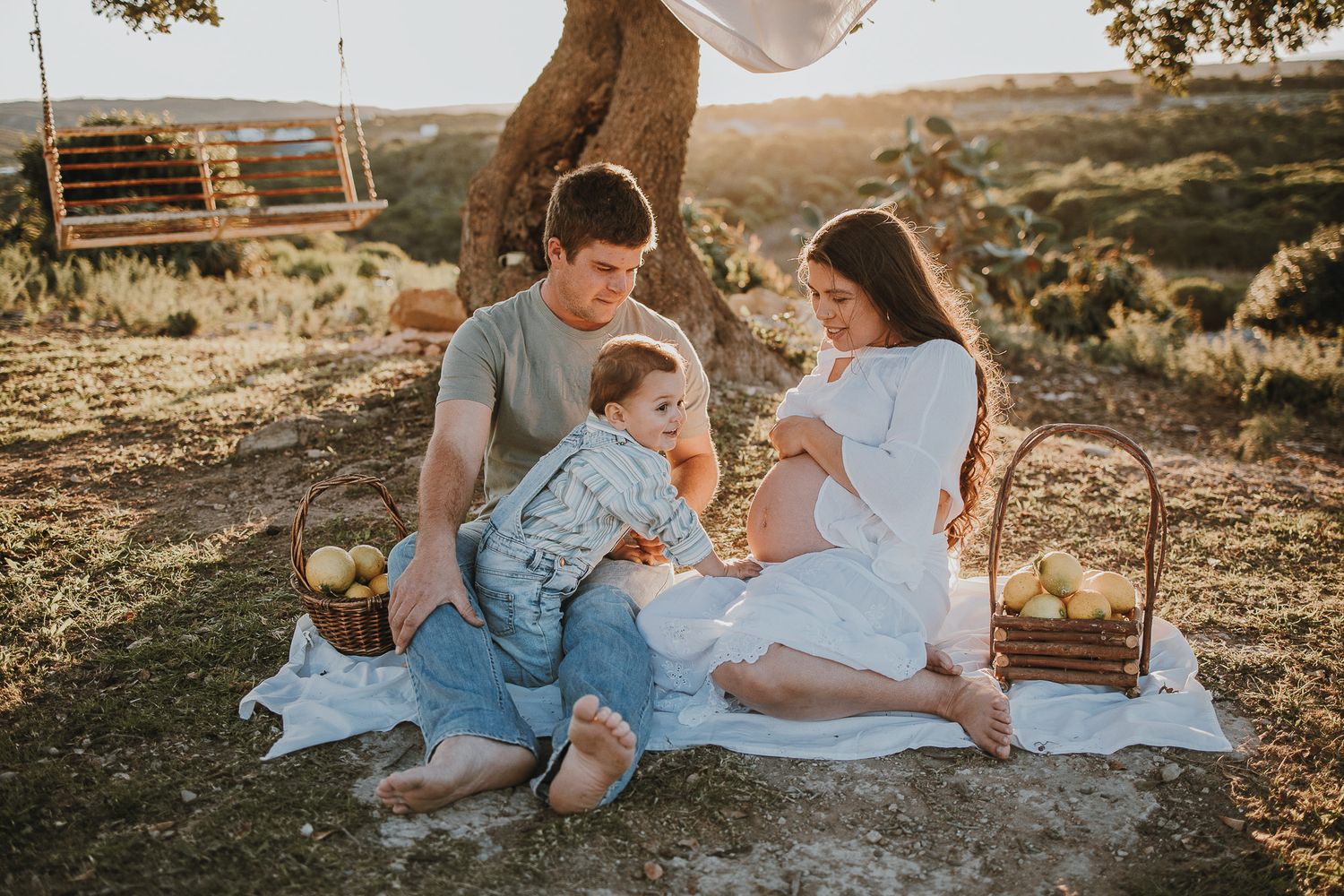 Family having picnic on hillside with wooden swing and scenic view.