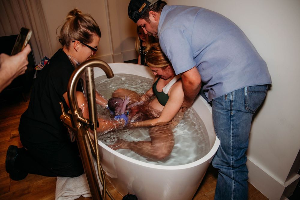 Birth support team assists with water labor in a home setting.