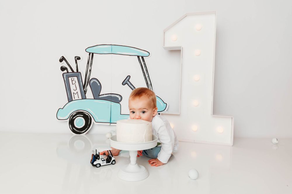 First birthday setup with golf theme decorations and number one prop on white background.