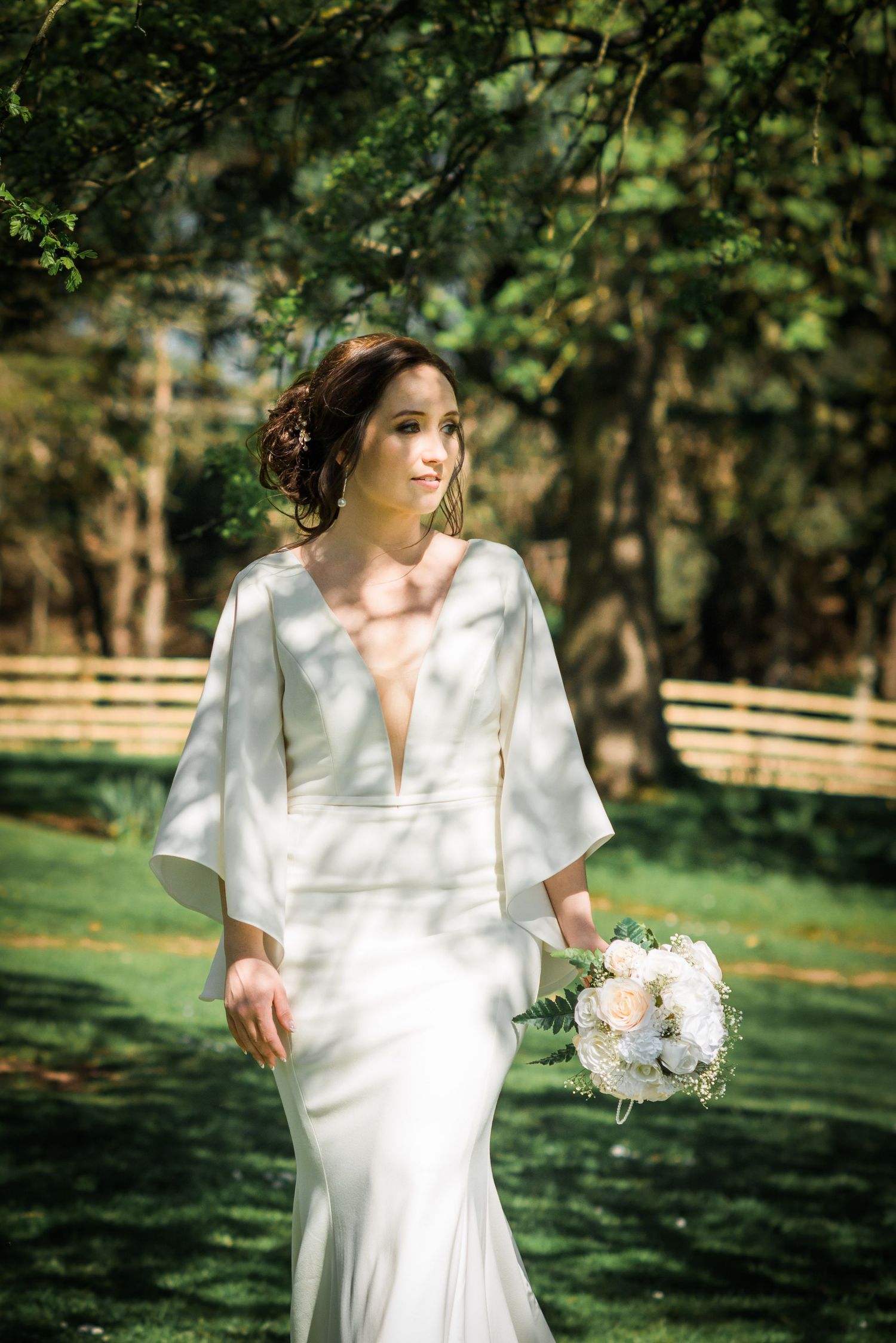 bride walks through dappled sunshine in her wedding dress