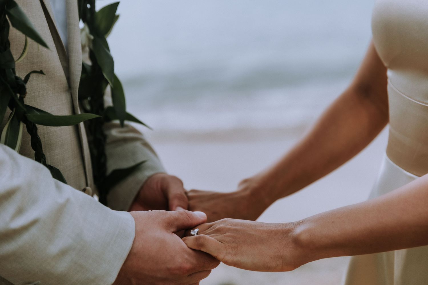 Close-up of hands touching during an intimate beach photography session.
