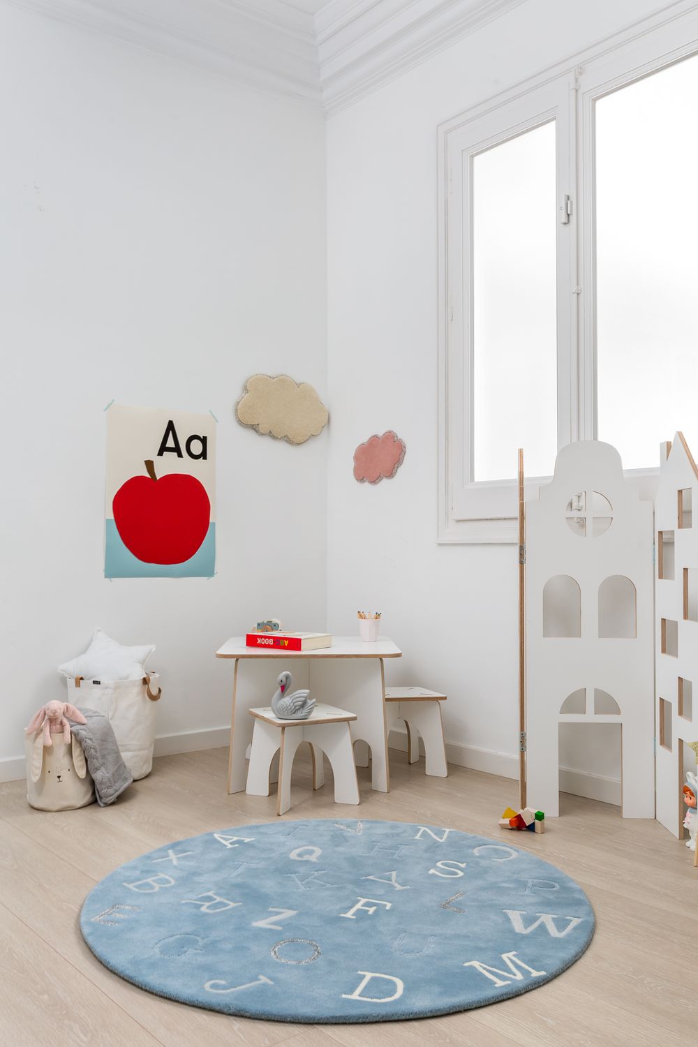 Bright children's playroom with alphabet rug, small table, chairs, and educational wall decor.