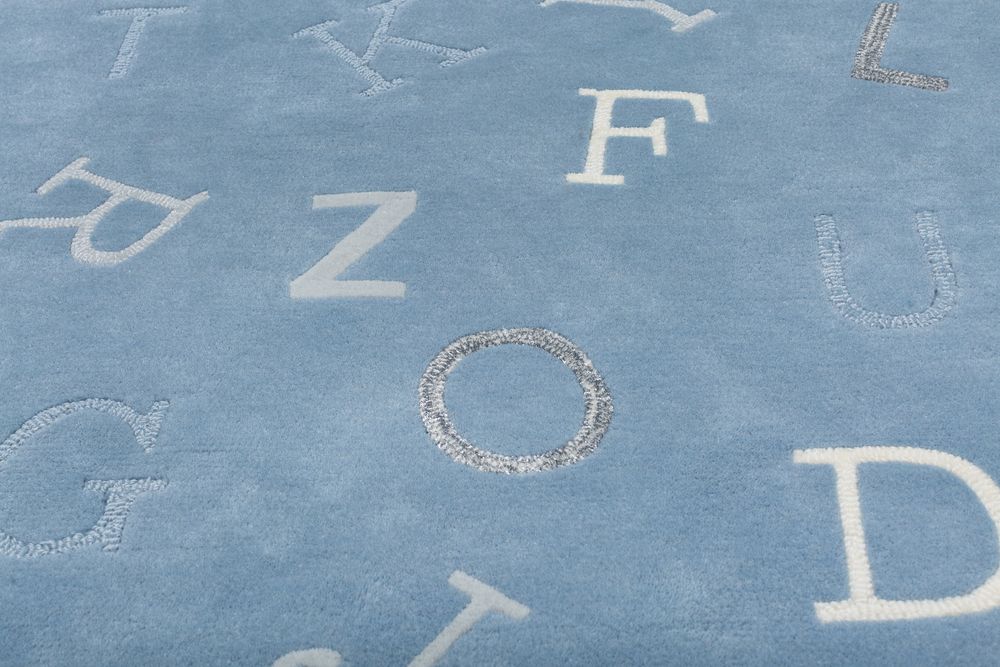 Close-up of blue alphabet rug featuring letters F, Z, G, O, D, U in white and grey tones.