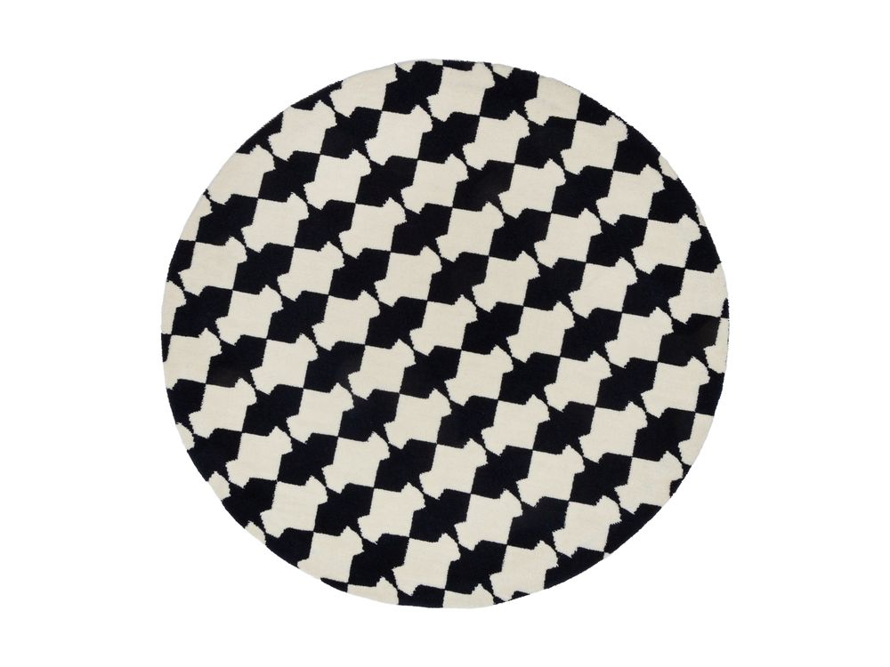 Round black and white houndstooth patterned rug with geometric cross shapes on neutral background.