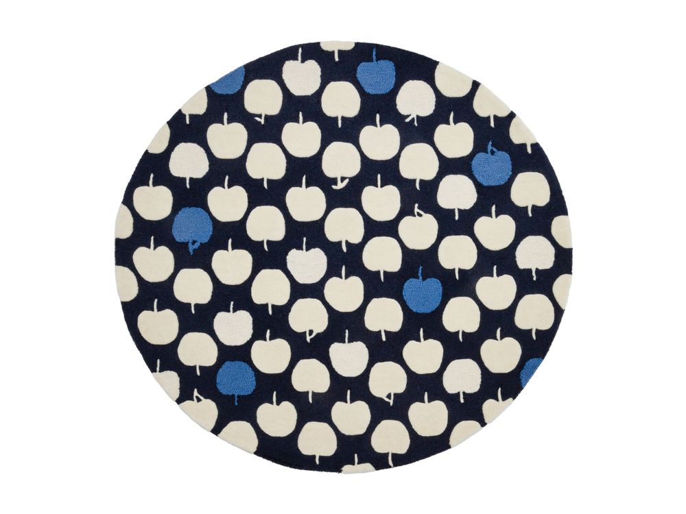 Round navy blue rug with repeating pattern of cream and blue apple motifs on dark background.