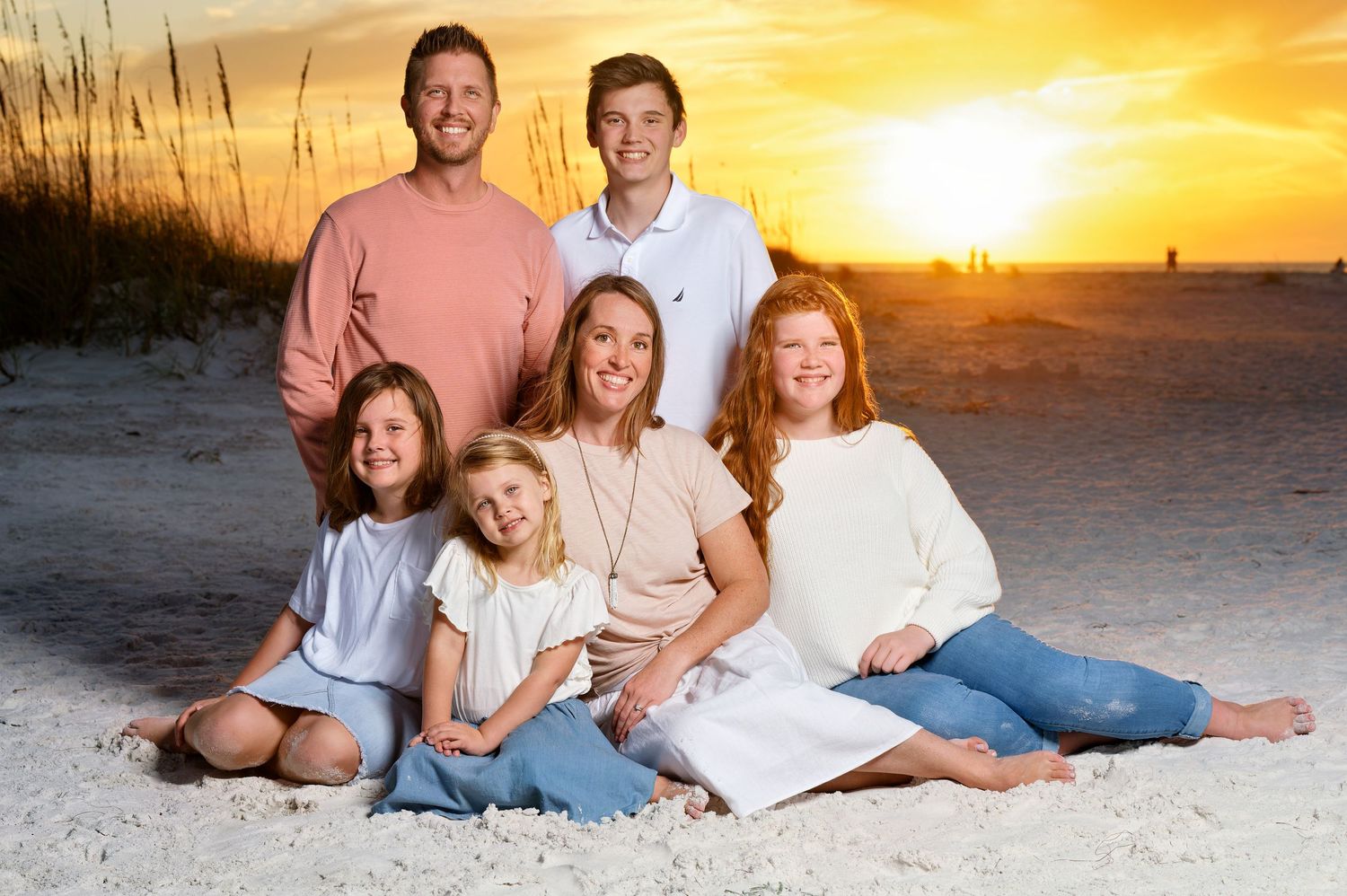 A family together on the beach against a beautiful sunset in Florida — a timeless beach sunset portrait.